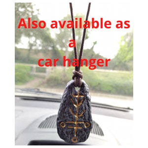 May include: A black and gold pendant with a symbol on it, hanging from a brown cord. Also available as a car hanger.