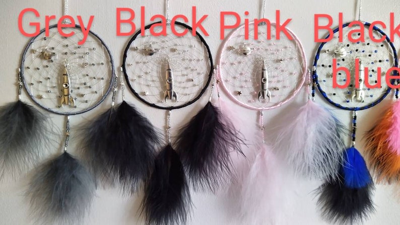 Pu&ograve; includere: Quattro acchiappasogni con cerchi e piume di diversi colori. I cerchi sono grigi, neri, rosa e neri con perline blu. Ogni acchiappasogni ha un ciondolo a razzo argentato.