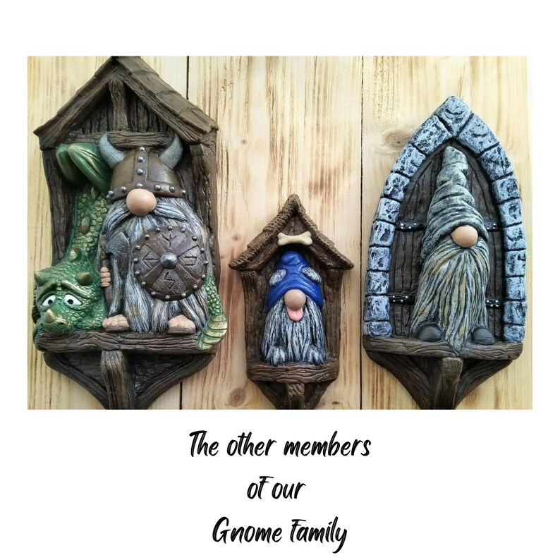 K&ouml;nnte beinhalten: Drei dekorative Zwergfiguren in Holzrahmen. Einer tr&auml;gt einen Wikingerhelm und h&auml;lt einen Schild, ein anderer tr&auml;gt einen blauen Hut und der dritte hat einen langen Bart. Der Text lautet "The other members of our Gnome Family."