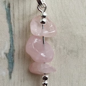 Puede incluir: Un collar de cristal de cuarzo rosa con cuentas plateadas y un cierre plateado. El collar est&aacute; hecho con tres piedras de cuarzo rosa.