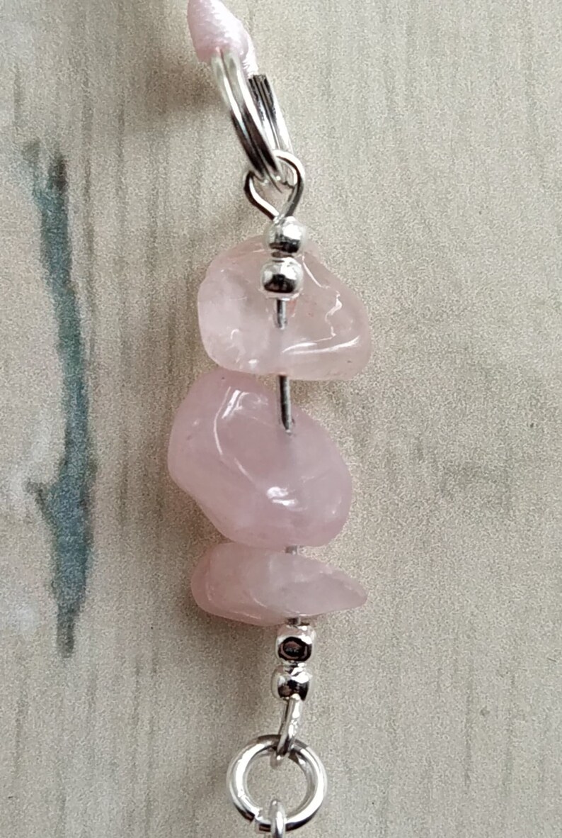 Puede incluir: Un collar de cristal de cuarzo rosa con cuentas plateadas y un cierre plateado. El collar est&aacute; hecho con tres piedras de cuarzo rosa.