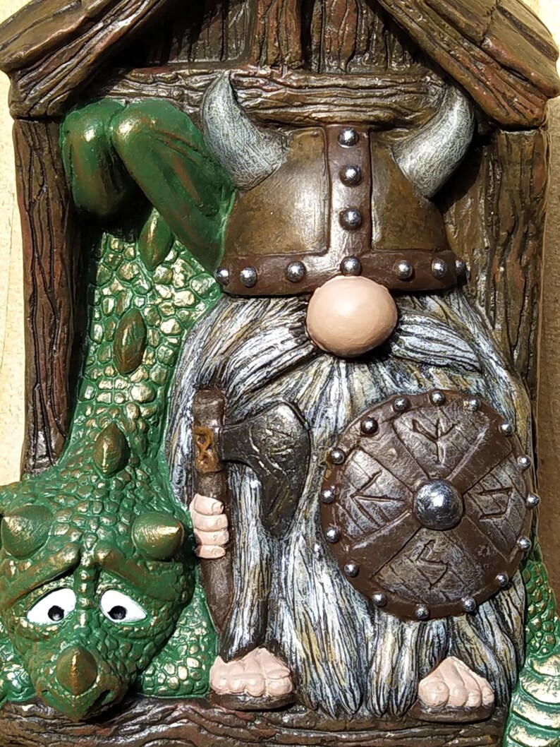 K&ouml;nnte beinhalten: Detaillierte Figur eines Wikinger-Zwergs und eines Drachen. Der Zwerg tr&auml;gt einen geh&ouml;rnten Helm, hat einen langen wei&szlig;en Bart und h&auml;lt eine Axt und einen Schild. Der gr&uuml;ne Drache hat einen traurigen Gesichtsausdruck.