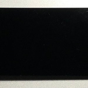 May include: A black rectangular tag with a silver key ring attached. The tag is blank and has a smooth surface.