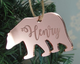 May include: Rose gold bear-shaped Christmas ornament with the name "Henry" engraved on it.