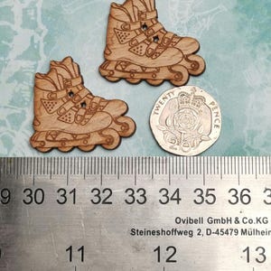 May include: Two wooden roller skate buttons, approximately 1.25 inches in diameter, with a 20 pence coin for scale.