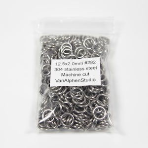 Peut inclure: Un sac en plastique transparent rempli de nombreux petits anneaux métalliques argentés. Les anneaux sont coupés à la machine et en acier inoxydable 304. L'étiquette indique : 12,5x2,0 mm #282, acier inoxydable 304, coupe machine, VanAlphenStudio.