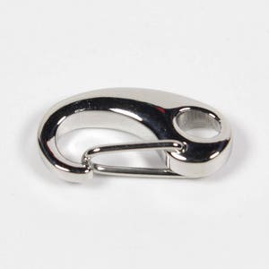 May include: A silver-toned metal trigger snap clasp. The clasp is a hook and loop design with a smooth, polished finish.