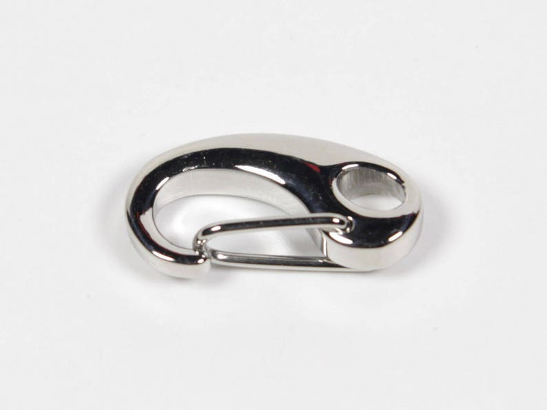 May include: A silver-toned metal trigger snap clasp. The clasp is a hook and loop design with a smooth, polished finish.