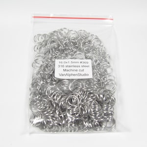 Könnte beinhalten: Ein klarer Plastikbeutel gefüllt mit zahlreichen silberfarbenen Metall-Sprungringen. Der Beutel hat einen roten Streifen oben und den Text "16.0x1.5mm #369 316 stainless steel Machine cut VanAlphenStudio."