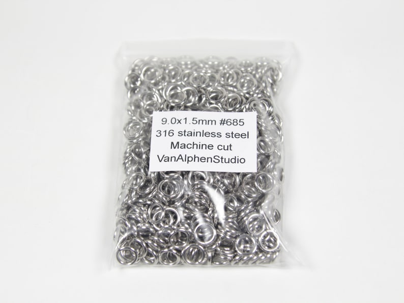 May include: A clear plastic bag filled with numerous small, shiny, silver-colored metal rings. The rings are machine cut and made of 316 stainless steel. Text on the label reads "9.0x1.5mm #685" and "VanAlphenStudio".