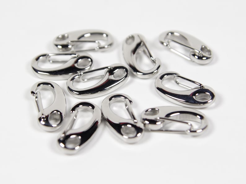 May include: A group of ten silver-toned metal lobster clasps. The clasps are oval-shaped with a spring-loaded gate.