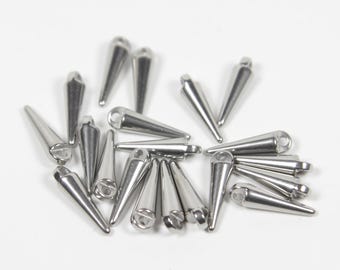 May include: A collection of small, silver-colored metal spikes, each featuring a smooth, conical shape and a flat base with a small circular hole for attachment. These metallic components have a polished, reflective finish and are arranged in a cluster.