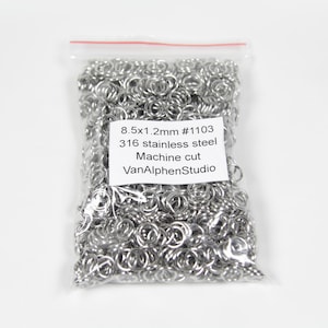 May include: A clear plastic bag filled with silver jump rings. The bag has a label that reads "8.5x1.2mm #1103 316 stainless steel Machine cut VanAlphenStudio".