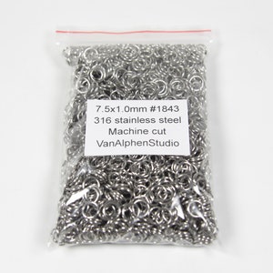 May include: A clear plastic bag filled with silver metal jump rings. The bag has a white label with the text "7.5x1.0mm #1843 316 stainless steel Machine cut VanAlphenStudio".