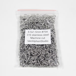 May include: A clear plastic bag filled with silver jump rings. The bag has a label that reads "8.5x1.5mm #754 316 stainless steel Machine cut VanAlphenStudio".