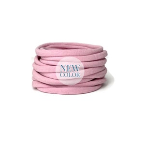 May include: A close-up of a pink, coiled, fabric hair tie. The hair tie is made of a soft, stretchy material and is perfect for holding hair in place.