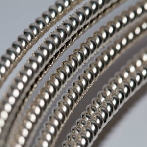 May include: Close-up of four silver guitar strings wound in a spiral pattern.