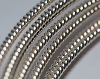 May include: Close-up of four silver guitar strings wound in a spiral pattern.