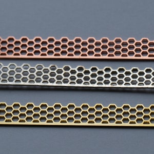 May include: Three metal strips with a honeycomb pattern. The strips are copper, silver, and gold.