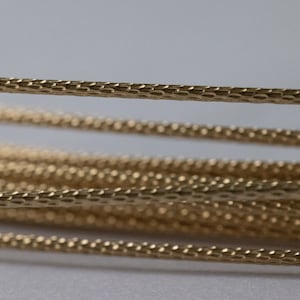 May include: Close-up of gold-colored braided wire with a textured surface.