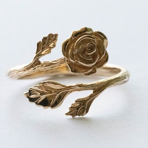 Peut inclure: Une bague en or avec une rose, des feuilles et un motif de branche torsadée.