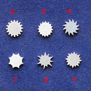 May include: Ten different metal gears with varying shapes and sizes. The gears are numbered 1 through 10.