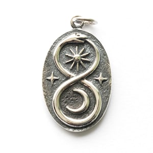 May include: Oval silver pendant featuring an ouroboros design, a snake eating its tail, with a sunburst in the center. The pendant has a textured background and three small star accents. The pendant is approximately 3.8 cm long.
