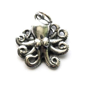 May include: A silver octopus pendant with detailed tentacles and a loop for a chain. The pendant is made of a shiny metal and is set against a white background. The octopus design is a popular nautical theme.