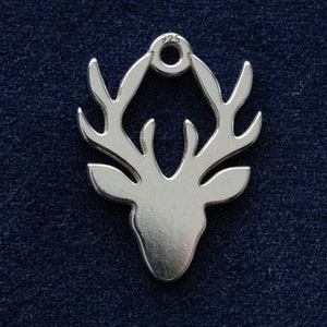 May include: A silver charm in the shape of a deer head with antlers. The charm has a loop at the top for attaching to a bracelet or necklace. The charm is marked with "925" on the loop.