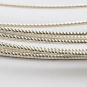 May include: Close-up of a set of silver-coloured guitar strings wound in a coil.