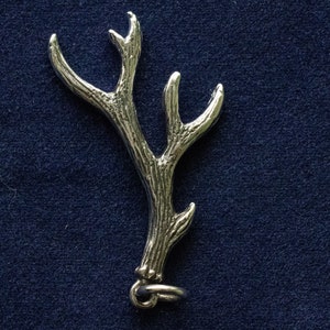 May include: A silver antler charm with a detailed design and a loop for attaching to a necklace or bracelet.