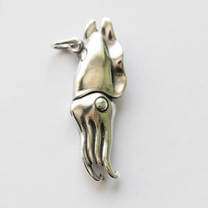 Può includere: Un ciondolo color argento a forma di calamaro. Il ciondolo presenta dettagli come tentacoli e un corpo arrotondato. Sembra essere fatto di metallo e ha un piccolo anello per attaccarlo a una catena. Lo sfondo è bianco.