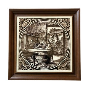 May include: A framed tile with a black and white illustration of a papermaking scene. The tile is surrounded by a decorative border with floral motifs. The text "De Papiermaker" is visible at the top of the tile.