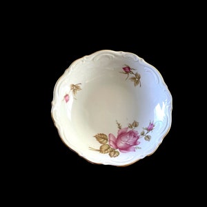 May include: A white porcelain bowl with a gold rim and a floral design featuring pink roses and green leaves.