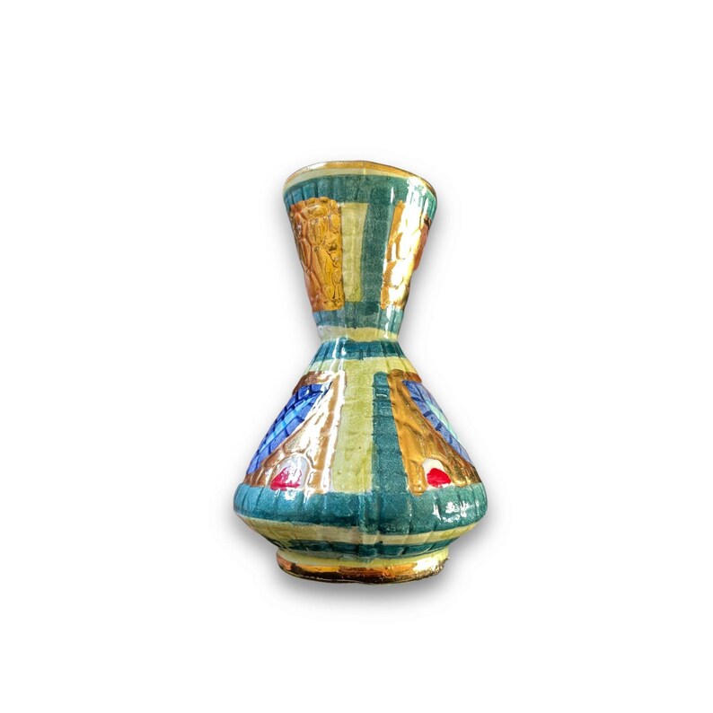 May include: A ceramic vase with a flared neck and a wide, rounded base. The surface features a grid pattern in shades of teal, gold, and blue, accented with small red details. The finish appears glossy, with a textured, hand-painted appearance.