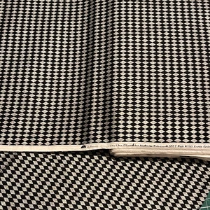 May include: Black and white fabric with a diamond pattern. The fabric has a subtle shimmer and is perfect for quilting, crafts, and home decor projects.
