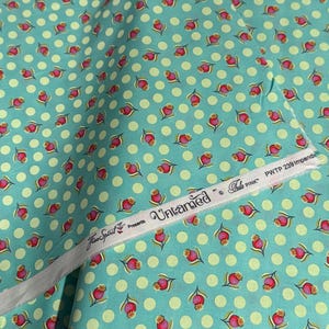 May include: Teal fabric with a white polka dot pattern and a repeating pattern of pink flowers. The fabric has a label that reads "Free Spirit Presents Untamed Tula Pink PWTP 239 Impendible".