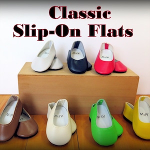May include: Classic slip-on flats in various colors, including white, black, red, brown, cream, green, and yellow. The shoes are arranged on a wooden surface.