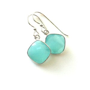 May include: A pair of silver dangle earrings with light blue square-shaped gemstones.
