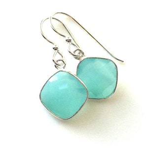 May include: A pair of silver dangle earrings with light blue square-shaped gemstones.