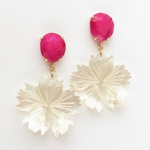 May include: A pair of dangle earrings with a pink gemstone and a white shell flower design.