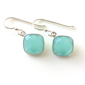 May include: A pair of silver earrings with light blue square-shaped gemstones.