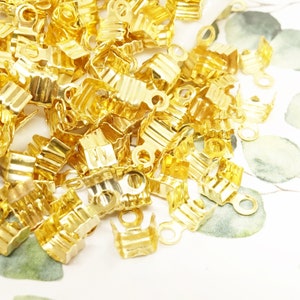 Puede incluir: Un montón de cierres de metal de color dorado con un bucle en un extremo. Los cierres están diseñados para ser utilizados en la fabricación de joyas.