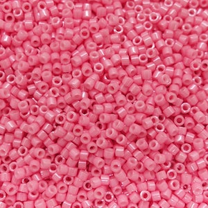 Könnte beinhalten: Nahaufnahme einer großen Menge kleiner, runder, rosa Perlen. Die Perlen haben eine glänzende, irisierende Oberfläche.