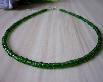May include: A green beaded choker necklace with a silver clasp.