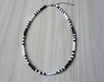 May include: A black and white beaded necklace with a silver clasp.