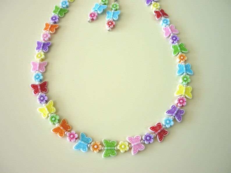 May include: A rainbow-colored necklace with butterfly charms and small flower beads. The necklace is made of plastic and is approximately 18 inches long.