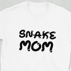 Op de afbeelding: Wit T-shirt met zwarte tekst die "SNAKE MOM" luidt in een bubbelachtig lettertype.