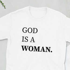 May include: White t-shirt with black text that reads "GOD IS A WOMAN."