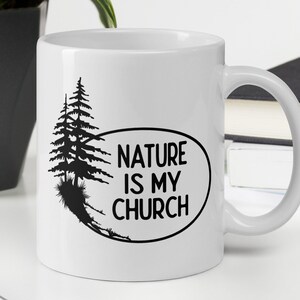 May include: White ceramic mug with a black silhouette of two pine trees and the text "NATURE IS MY CHURCH" in a black oval.
